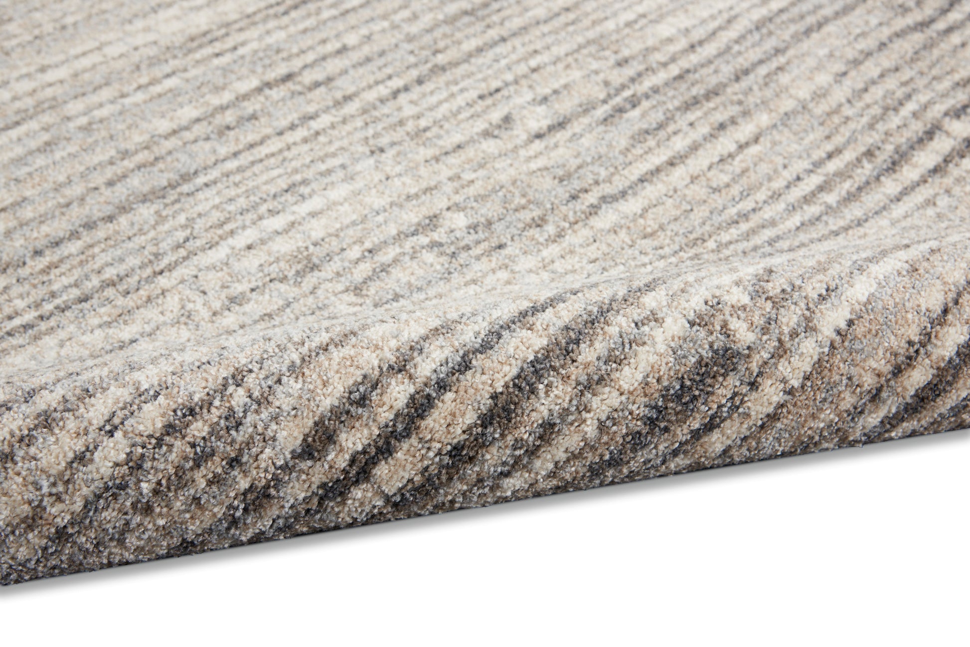 Close-up of a beige and gray striped area rug with soft textured pile and rolled edge.
