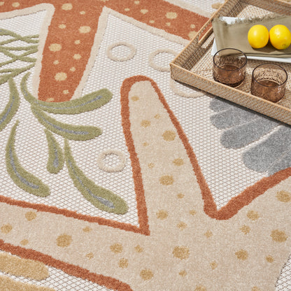 Beige outdoor rug with abstract orange and tan floral pattern and green leaf accents; wooden tray with two glasses and lemons