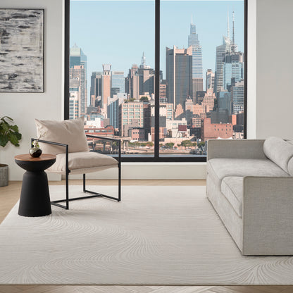 Modern living room: light gray sofa, beige armchair with black frame, round black table, plant, abstract art, skyline view.