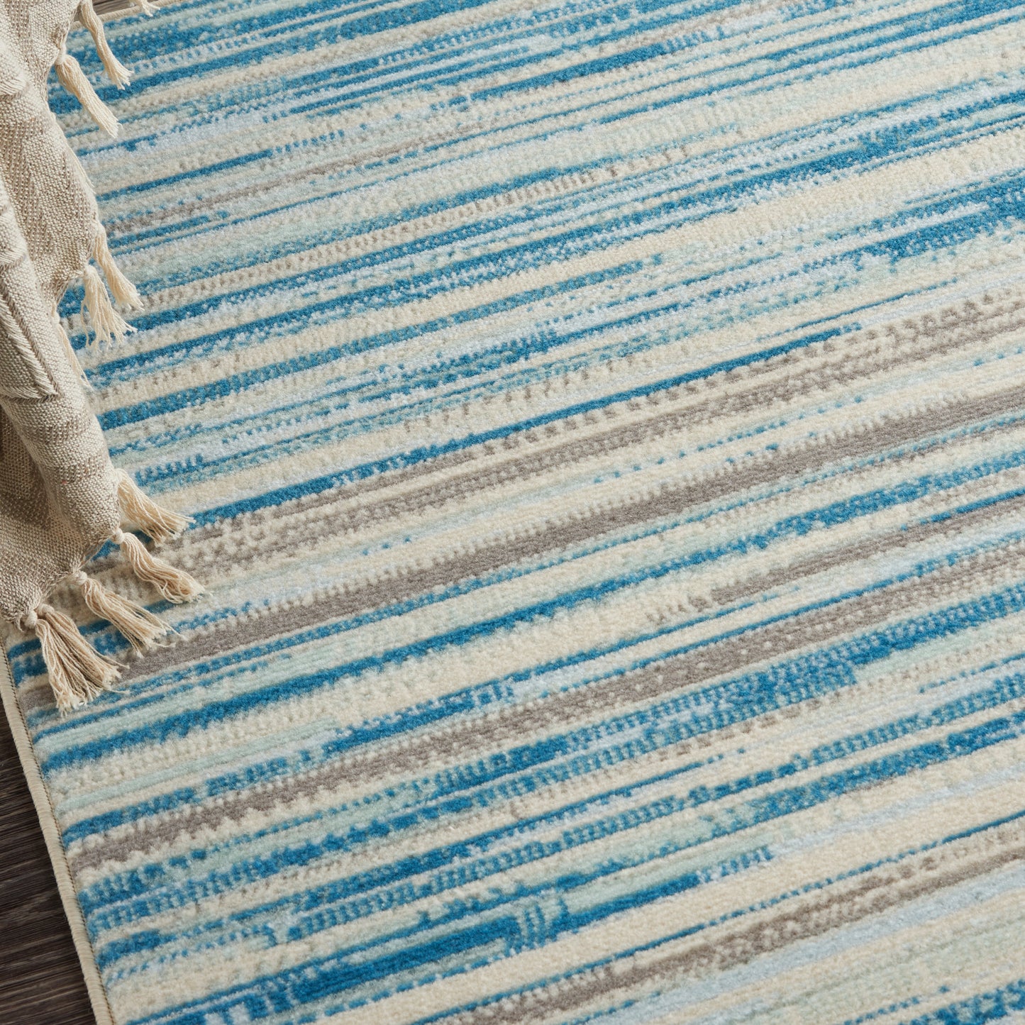 Blue and cream striped woven rug with fringed ends; soft textured, modern coastal style.