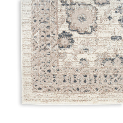 Beige vintage-style area rug with blue-gray floral motif and ornate border; rectangular, soft low-pile decor.