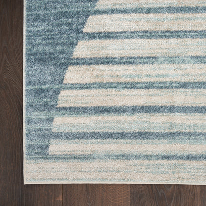 Blue and cream striped area rug with irregular horizontal bands on dark wood floor.