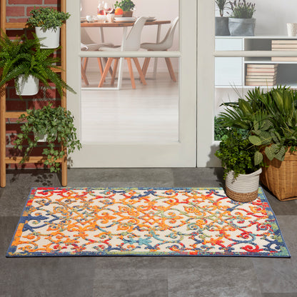 Vibrant multicolor outdoor rug with a floral-scroll pattern and blue border at a doorway, framed by potted plants.
