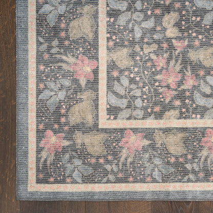 Rectangular navy area rug with pink flowers and cream vines; pale border stripes on a dark wood floor.
