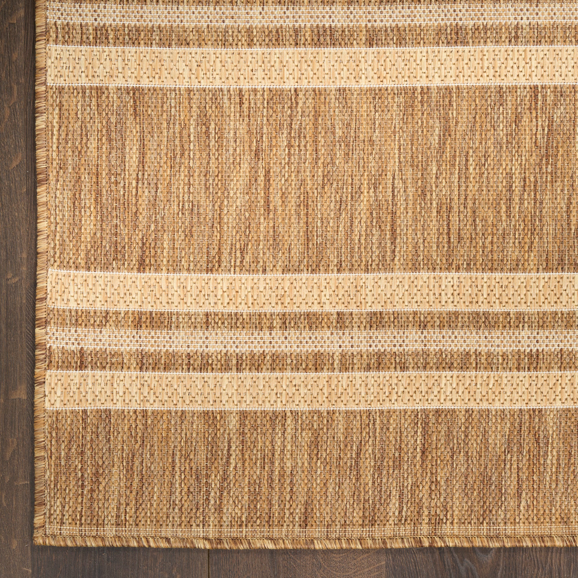 Natural fiber jute rug with beige and tan horizontal stripes, textured weave and fringe edges.