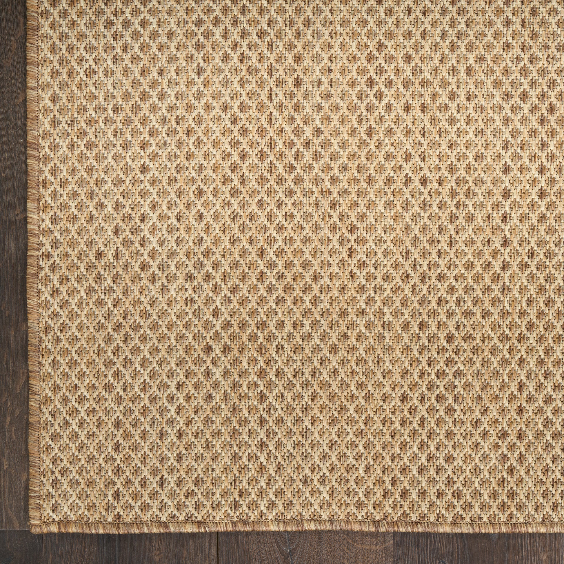 Beige woven jute rug with small diamond lattice pattern & dark brown border along left & bottom edges.