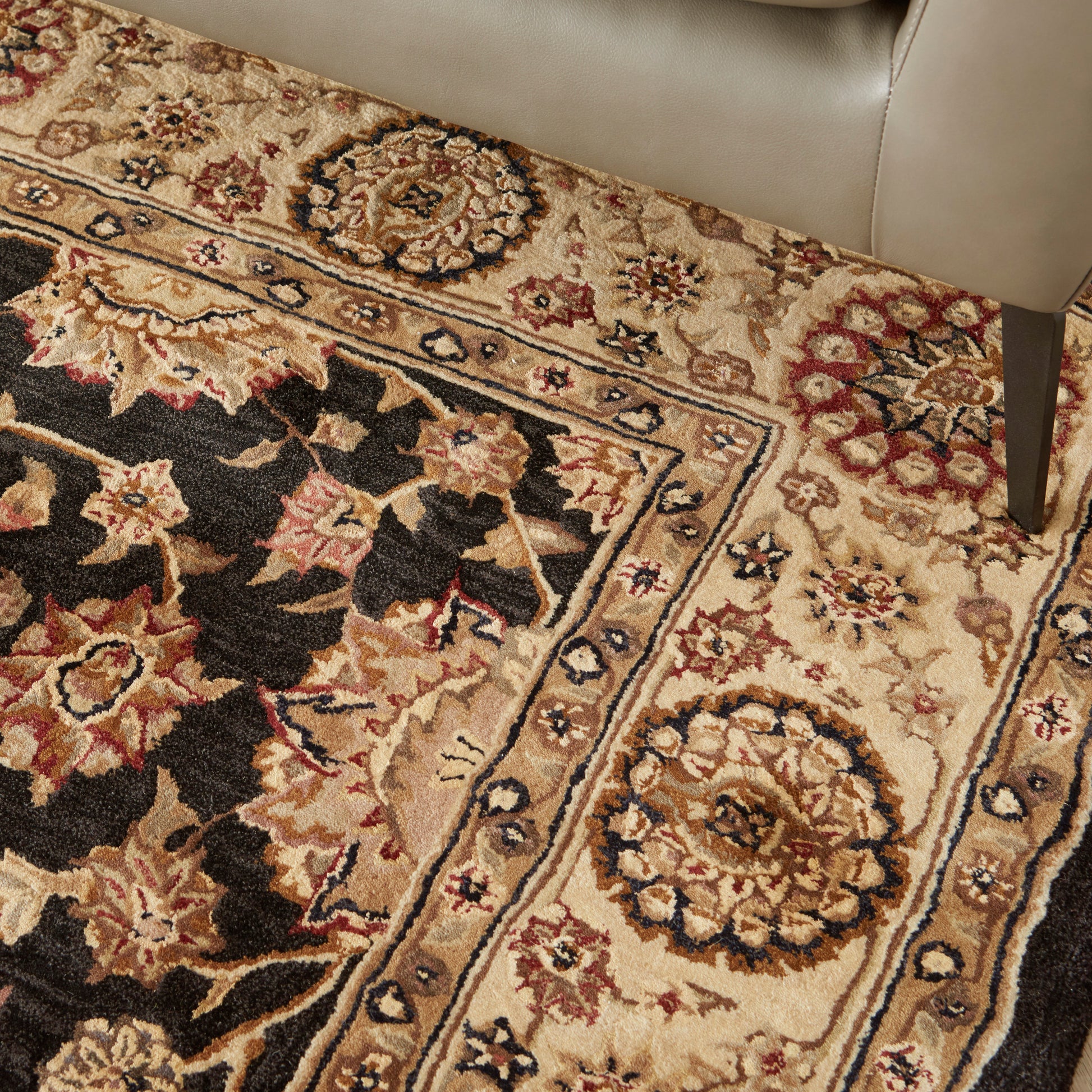 Persian-inspired rug with cream background, ornate floral medallions, black field, and red, blue, gold accents; bordered.