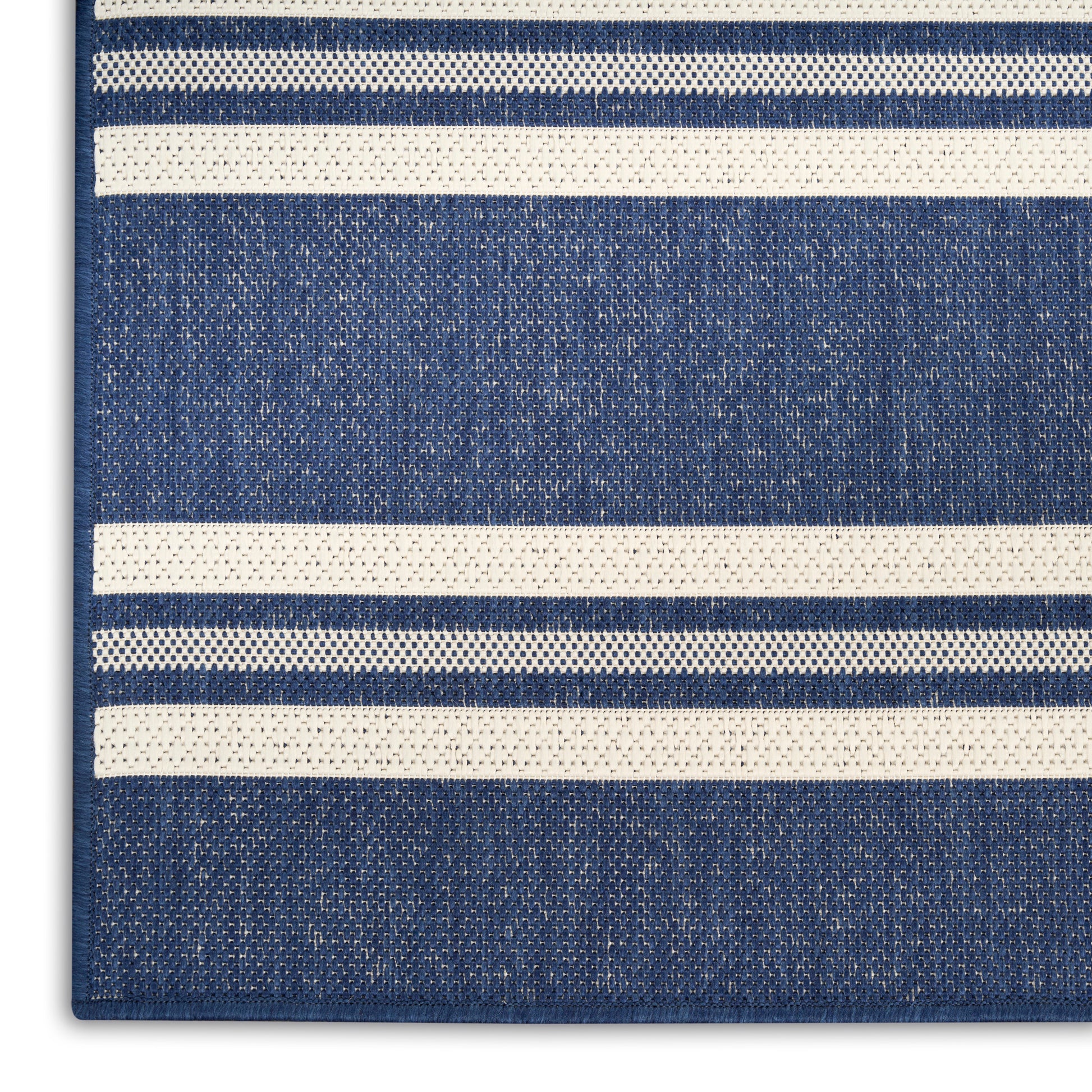 Close-up of a blue rug with white horizontal stripes; textured weave and visible edge.