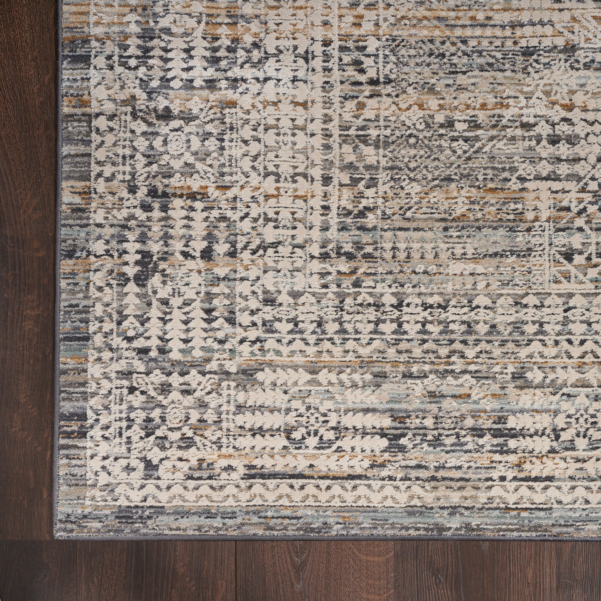 Distressed oriental runner rug in cream, gray, blue and tan tones with an ornate border on dark wood floor.