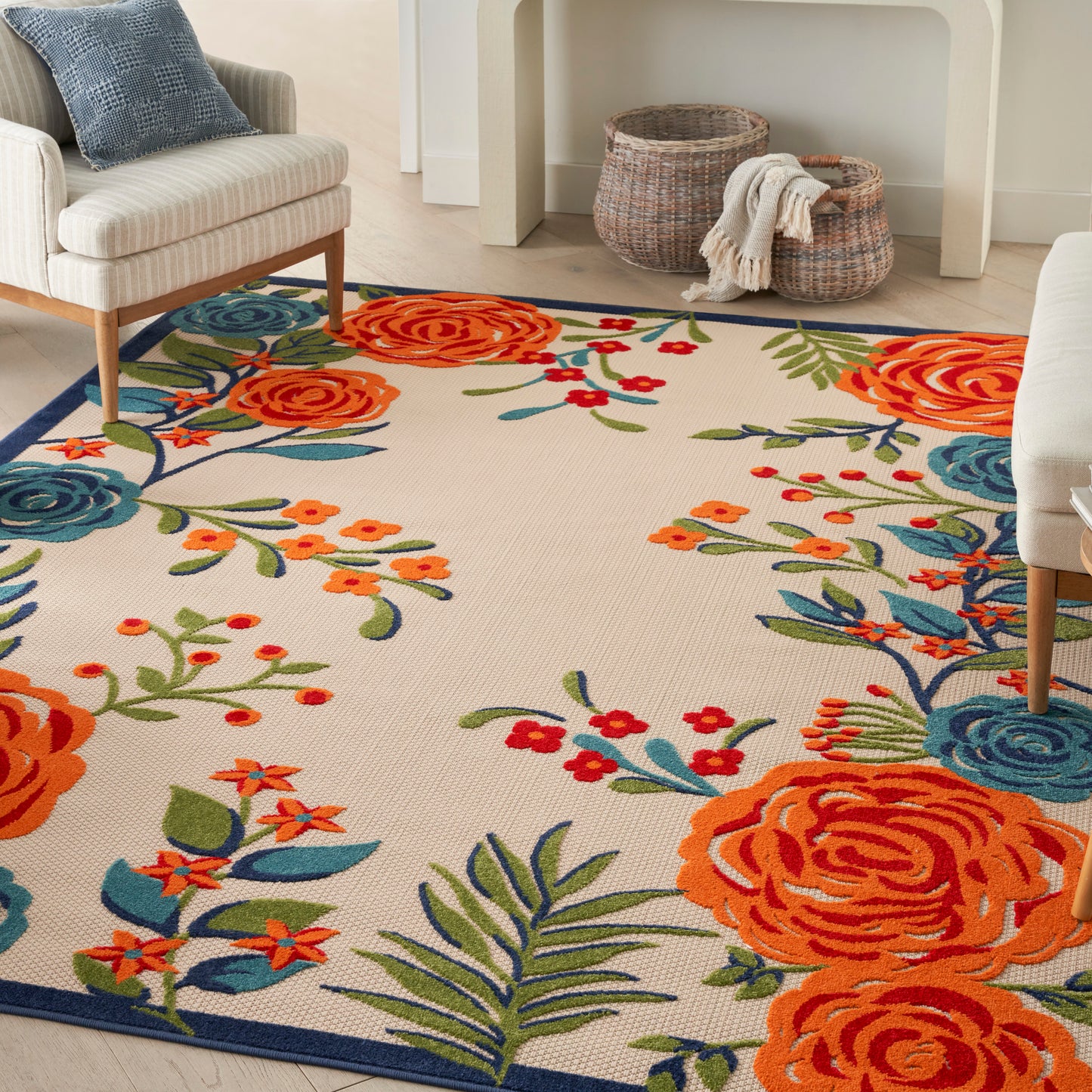 Colorful floral area rug with orange roses and blue blooms on cream background; blue border brightens a cozy living room.