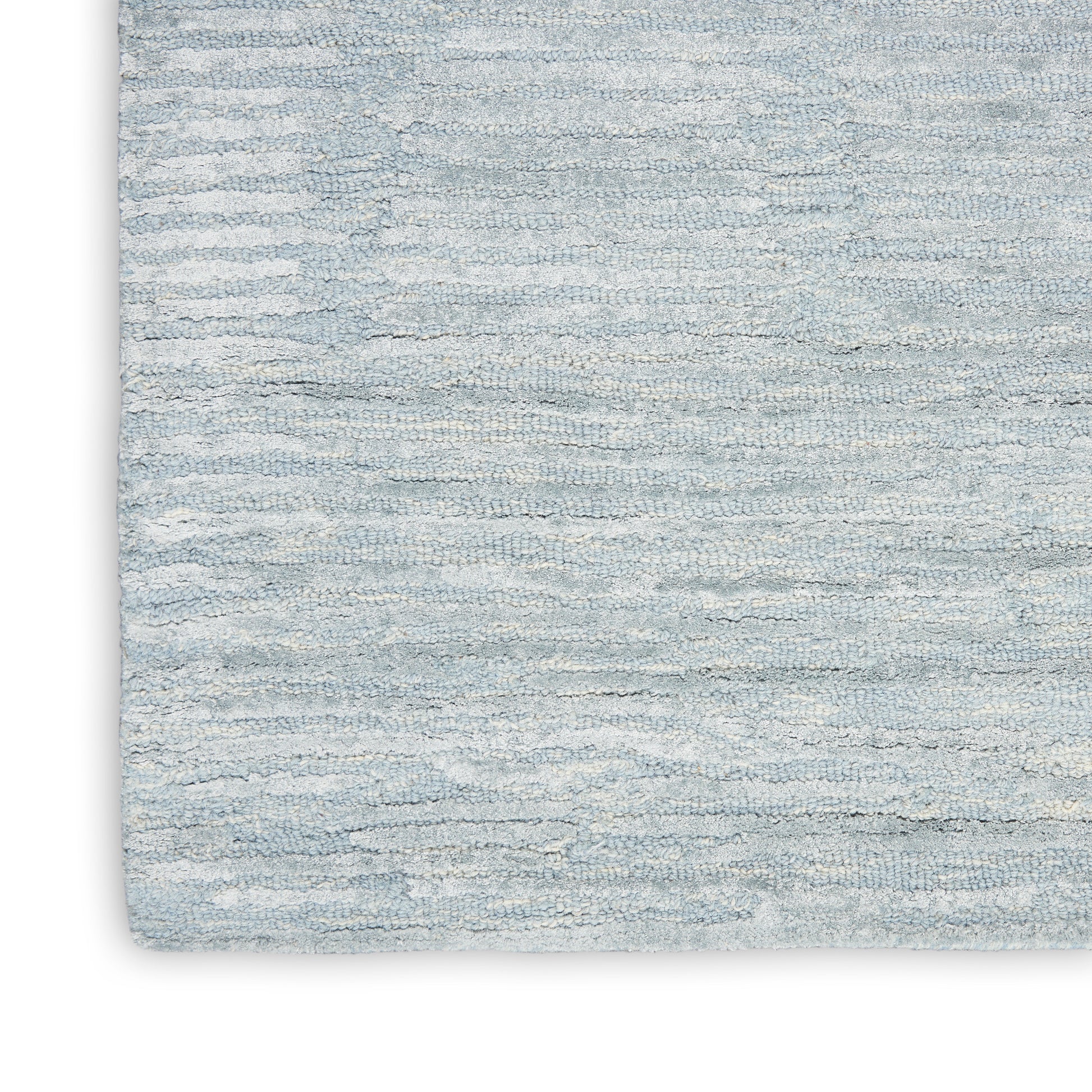 Close-up of a light blue-gray rug with a subtle horizontal wave texture.