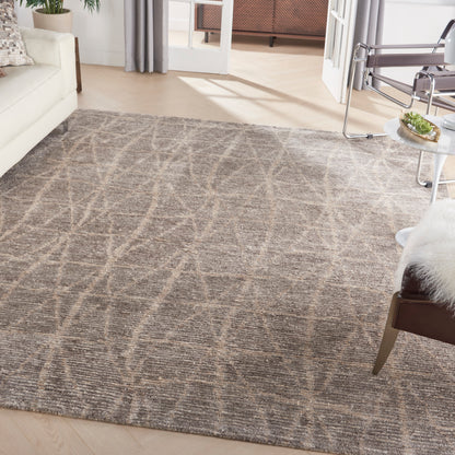 Neutral gray area rug with abstract beige curved lines in a modern living room on a light wood floor.