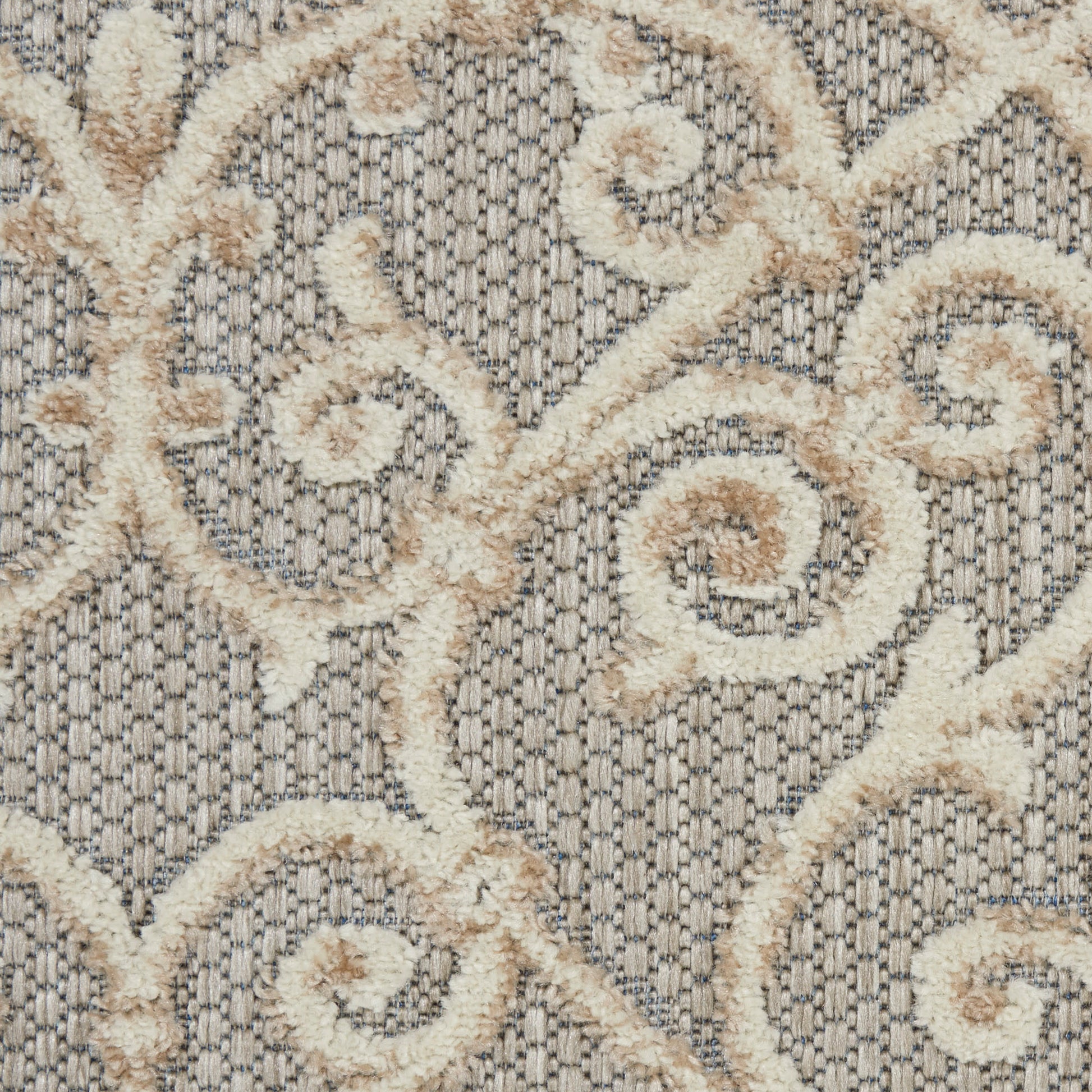 Cream boucle scroll pattern on textured gray woven rug.