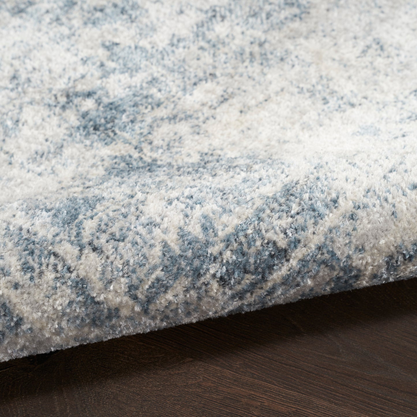Blue and ivory marbled area rug with plush pile on dark wood floor.