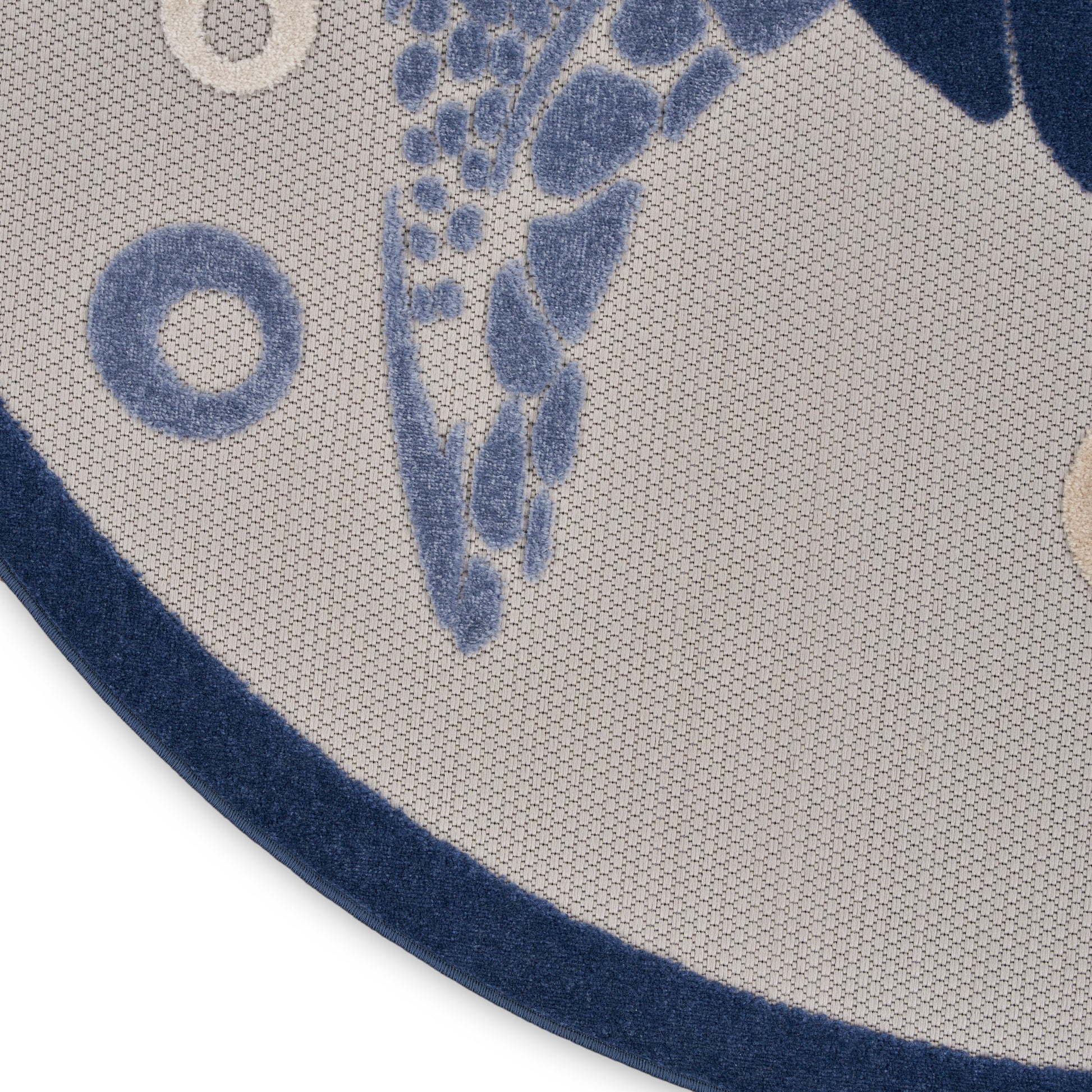 Round beige rug with blue nautical motif and navy border; woven texture.