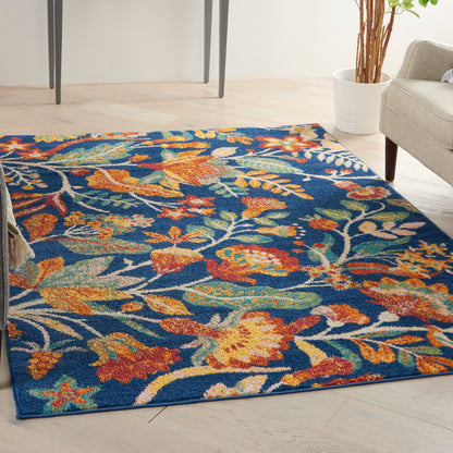 Vibrant floral area rug with orange, yellow, teal, and white blossoms on a deep blue background in a modern living room.