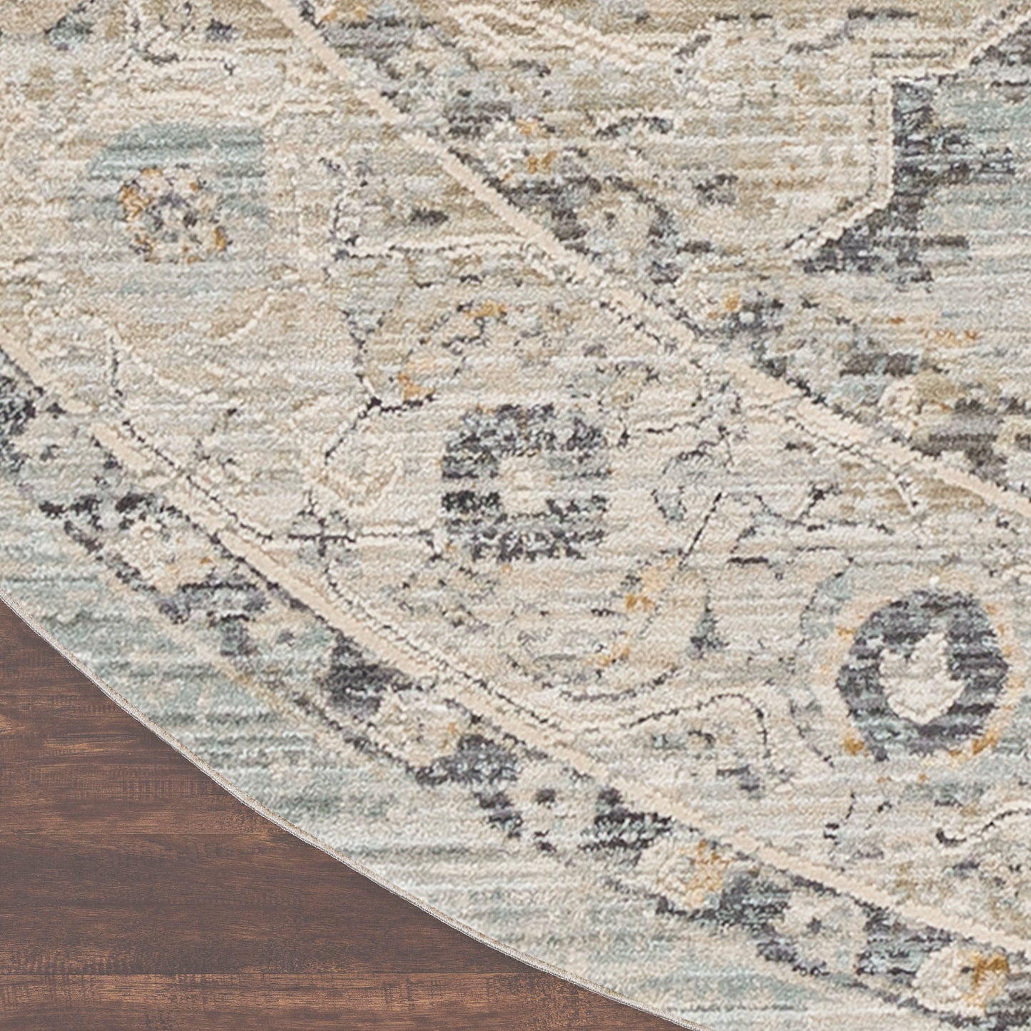 Round distressed oriental rug in ivory, blue, gray & tan tones on dark wood floor.