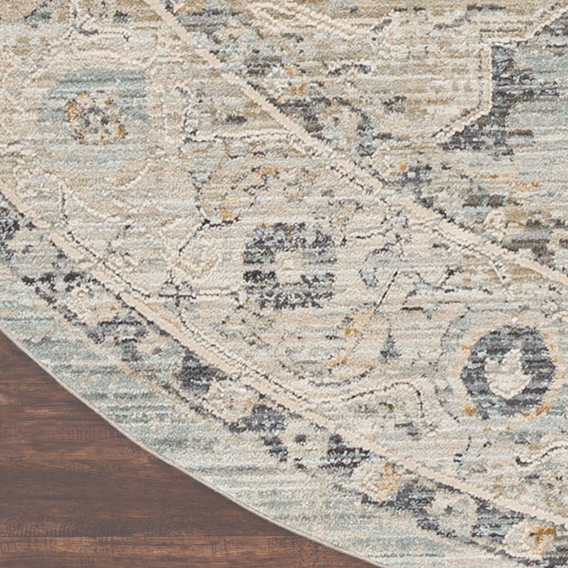 Round distressed oriental rug in ivory, blue, gray & tan tones on dark wood floor.