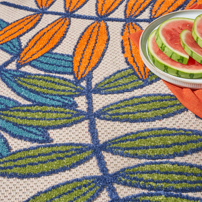 Round woven rug with blue stems and orange and green leaves on beige