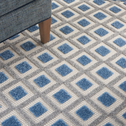 Blue diamond-pattern area rug with gray borders on a light gray field; sofa leg visible.