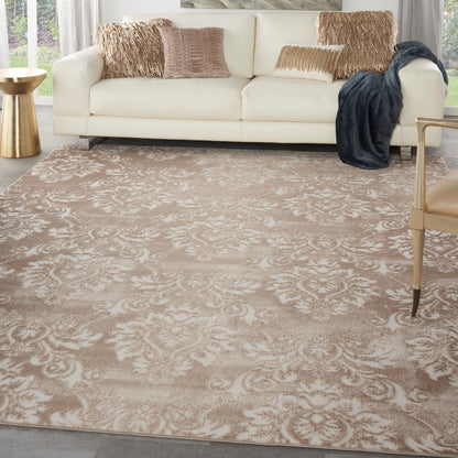 Beige damask area rug on a living room floor, with a cream sofa and beige pillows, a gold side table, light curtains, and a dark throw blanket.