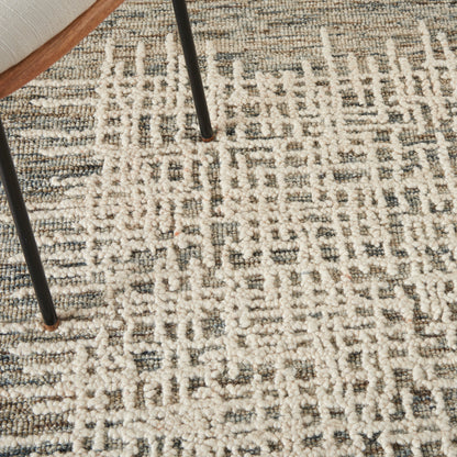 Neutral cream-gray geometric rug with textured loop pile, under black metal chair legs.