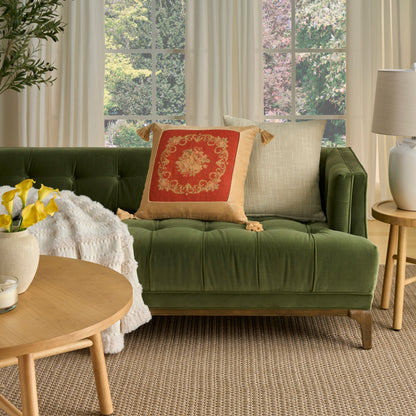 Green velvet tufted sofa with red-gold pillow, beige cushion, cream throw; round wooden coffee table with yellow flowers.