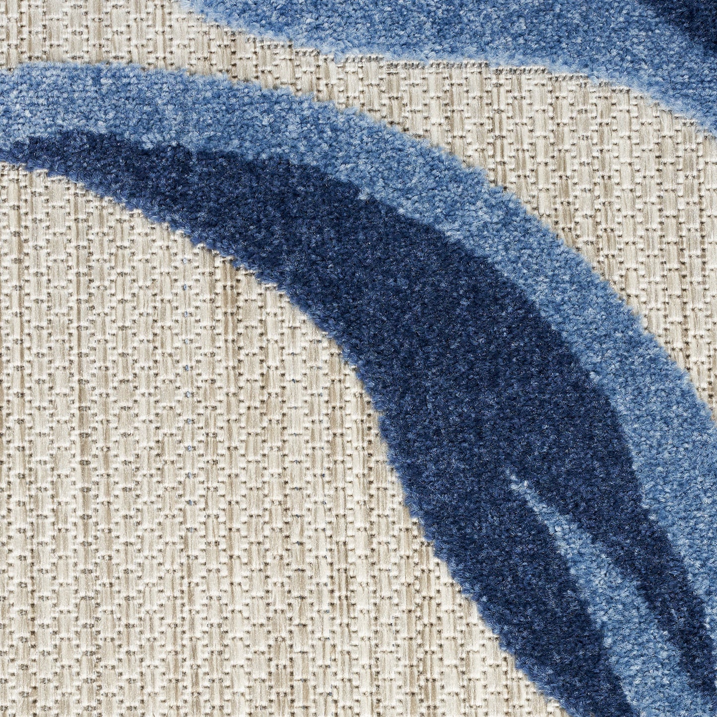 Blue curved stripe rug with gradient from light to dark blue on beige textured woven backdrop; plush pile.