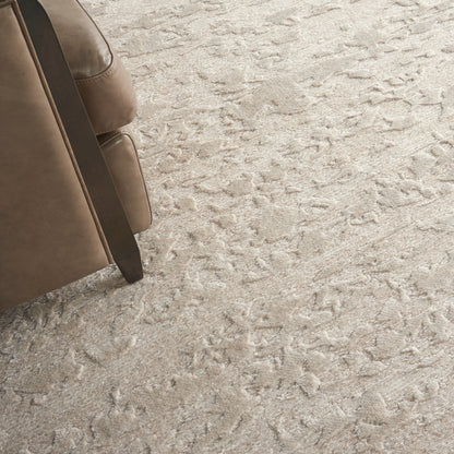 Beige leather sofa with dark wood legs on a light textured shag carpet.