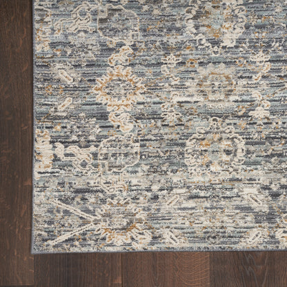 Distressed blue-gray Oriental area rug with ivory and tan floral motifs and a light blue border on dark wood floor.