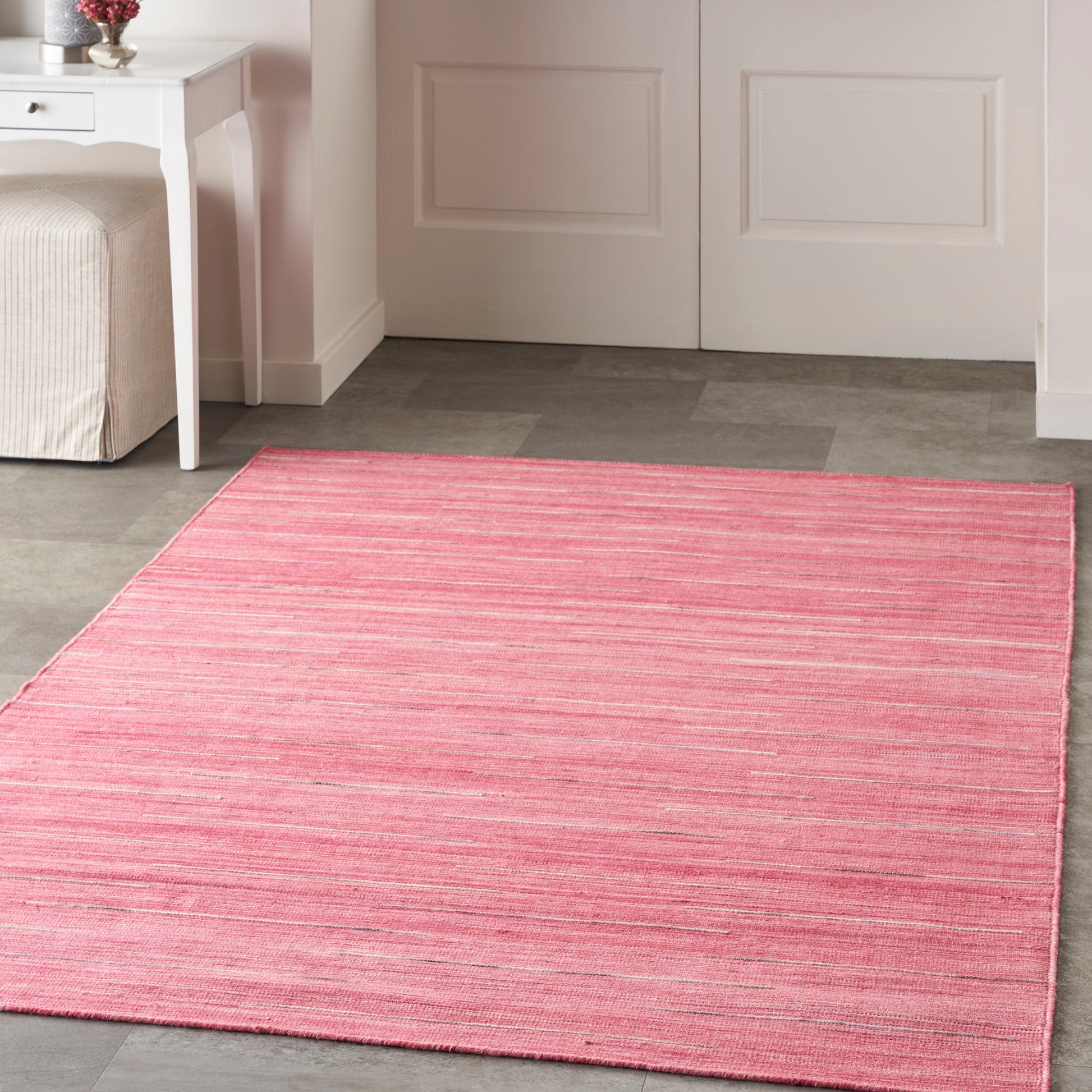 Soft pink striped area rug on gray tile floor in a bright room, rectangular and cozy.