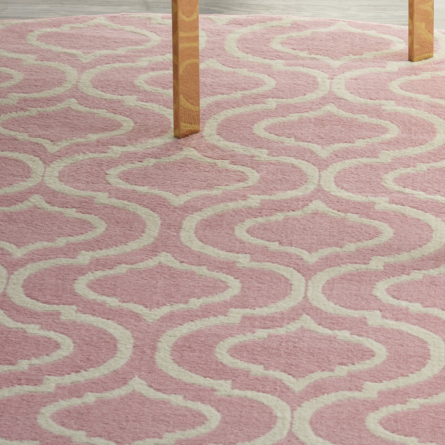 Soft pink shag rug with cream geometric trellis pattern under wooden table legs.