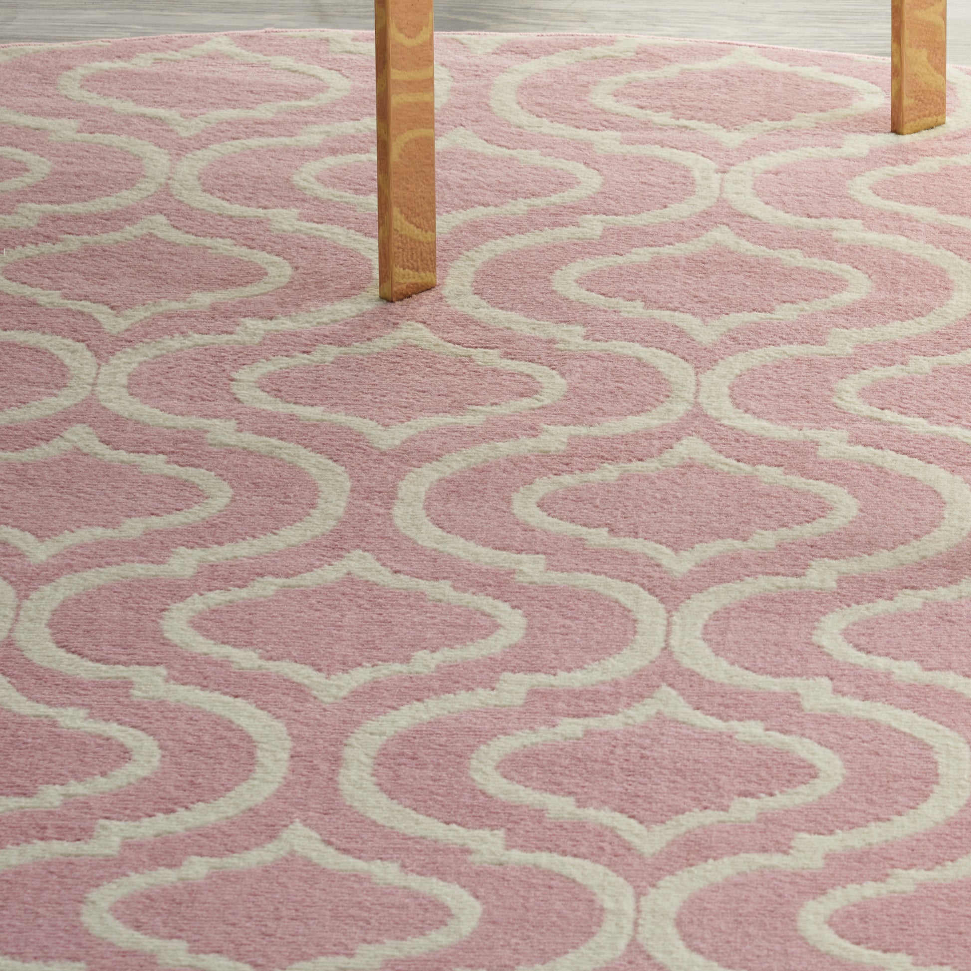 Soft pink shag rug with cream geometric trellis pattern under wooden table legs.
