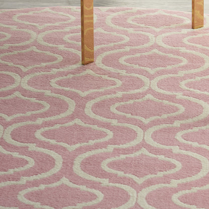 Soft pink shag rug with cream geometric trellis pattern under wooden table legs.
