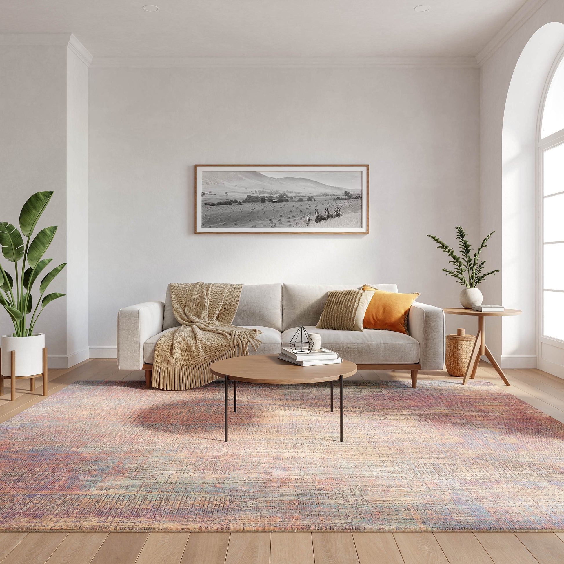 Cozy modern living room with beige sofa, cream throw, orange cushion, round wood coffee table, pastel rug, green plants.