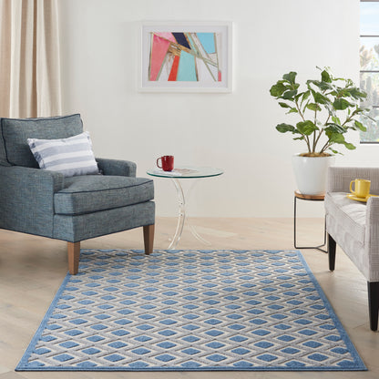 Cozy contemporary living room with blue geometric rug, blue armchair, glass coffee table, potted plant, abstract art.