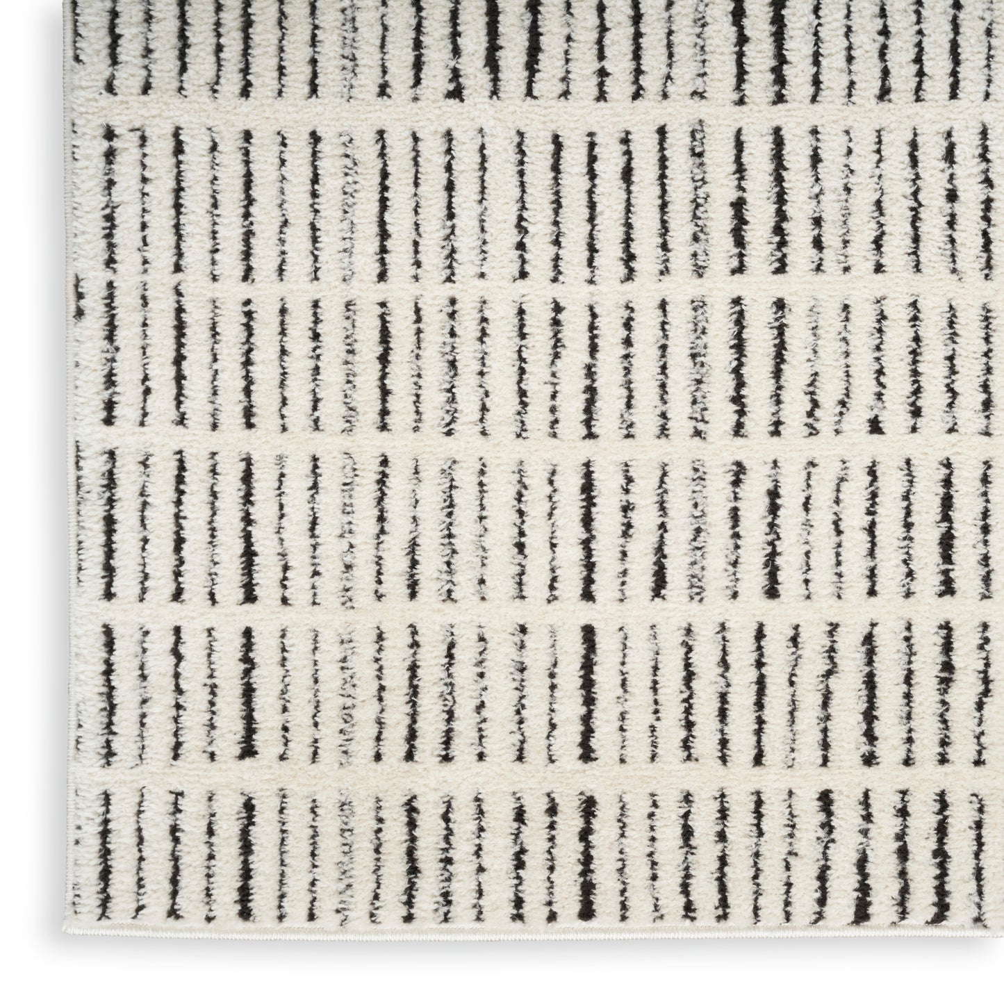 Rectangular cream rug with black vertical stripes, textured woven surface and white fringe along the edge.