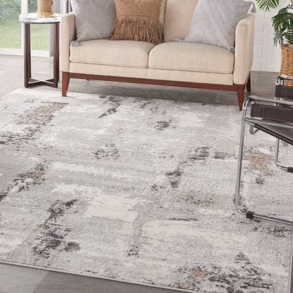 Living room scene with beige sofa on wooden legs, light gray abstract rug, glass-top side table, chair, and potted plant.