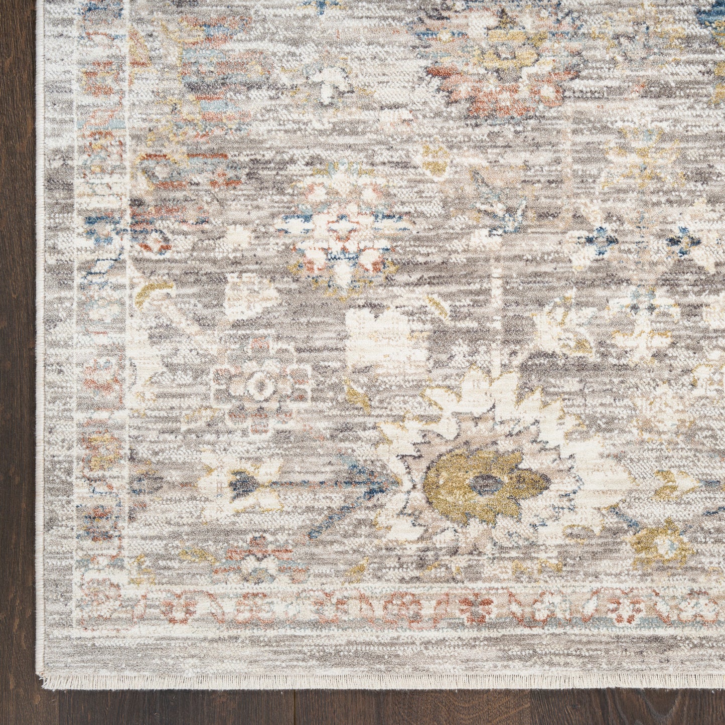 Distressed vintage-style area rug with muted floral pattern in ivory, beige, blue and gold; rectangular woven pile.