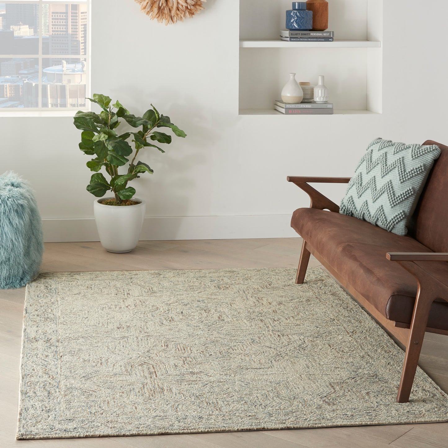 Mid-century brown leather sofa with a teal zigzag cushion, beige textured rug, potted plant, and white wall shelves.