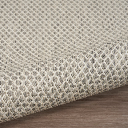 Beige and gray woven fabric rug with a subtle geometric texture, rolled on a wood floor.