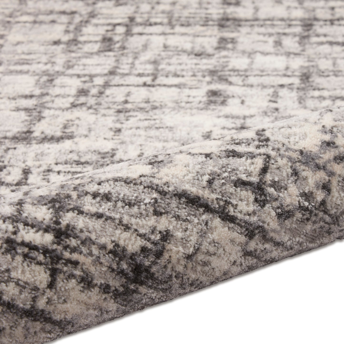 Soft plush rectangular area rug in grey & ivory abstract distressed pattern with a folded edge.