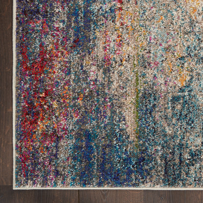 Shaggy, multicolored abstract area rug with blues, teals, reds and creams, cream border on dark wooden floor.