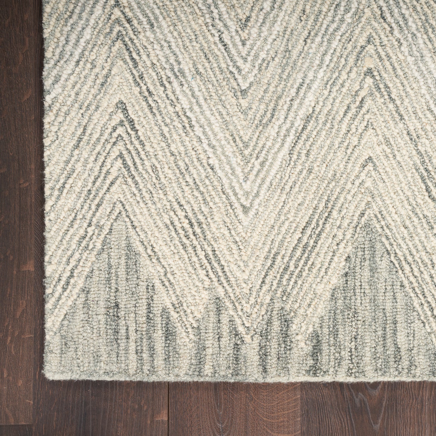 Cream and gray chevron rug with shaggy texture on dark wood floor.