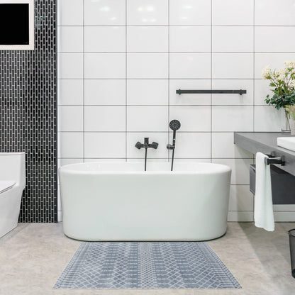 White freestanding oval bathtub with matte black fixtures in a modern white-tiled bathroom; blue-gray geometric rug.
