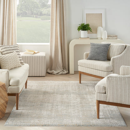 Neutral living room with cream striped armchairs, pale patterned rug, curved cream console, plant and white vases.