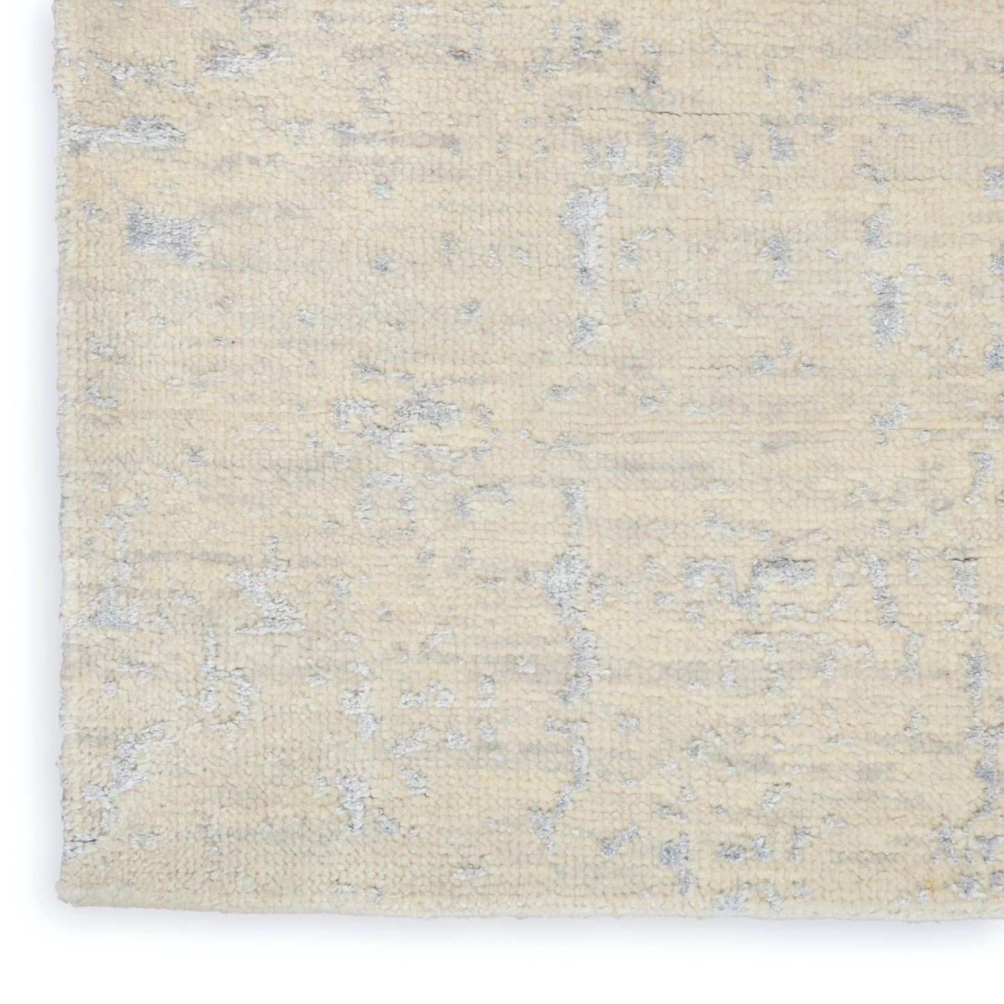 Beige area rug with subtle gray-blue abstract pattern; short pile, textured surface.