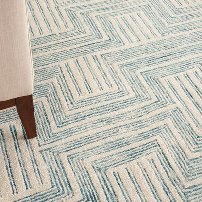 Cream rug with teal geometric nested-square lines; woven, modern living room accent.