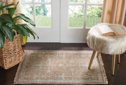 Beige oriental rug with fringe on dark wood floor, fur-covered stool with open book nearby, potted plant in woven basket.