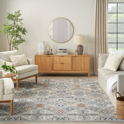 Cozy living room with mid-century sideboard, round mirror, beige sofas, greenery, and a blue-gray patterned rug.